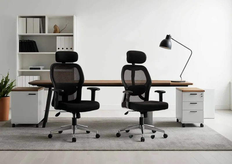 Two black mesh chairs at a desk in a bright office